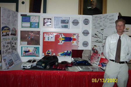 1993 Ford Taurus - A man in a white dress shirt and tie stands beside a tri-fold display board covered in automotive concept sketches and renderings, with sev…