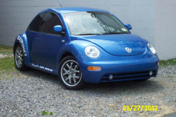 1993 Ford Taurus - A blue Volkswagen Beetle is parked on a gravel surface with a white wall in the background.