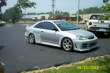 1993 Ford Taurus - Silver coupe with body kit and custom wheels parked next to a white pickup truck.
