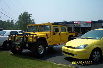 1993 Ford Taurus - A yellow Hummer H1 pickup truck is parked outside a building with other vehicles.
