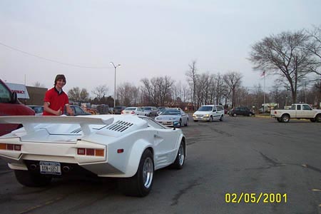 1993 Ford Taurus - A white sports car with a prominent rear wing is parked in a lot with other vehicles visible.