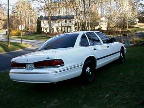 1996 Ford Crown Victoria - White 1996 Ford Crown Victoria sedan seen from the rear quarter angle, parked on a grassy lawn.