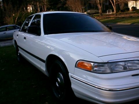 1996 Ford Crown Victoria - A white sedan is parked on a grassy area with another car in the background.