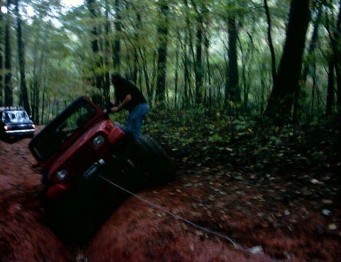 1990 Ford Bronco - Two Jeeps off-roading in a wooded area, one gets stuck in the mud.