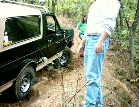 1990 Ford Bronco - A 1990 Ford Bronco is seen on a dirt trail, with two people in the background.