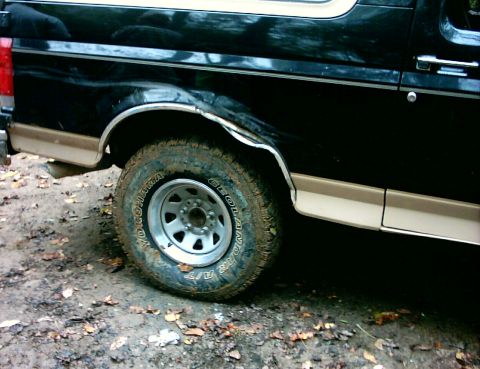 1990 Ford Bronco - Side view of a black and tan 1990 Ford Bronco, focusing on the rear wheel and fender.
