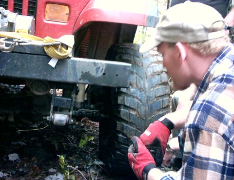 1990 Ford Bronco - A person in red gloves works near the tire and fender of a red vehicle.