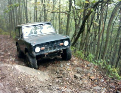 1990 Ford Bronco - Ford Bronco navigates a steep, rocky, wooded path in the rain.