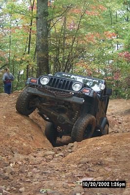 1990 Ford Bronco - A black Jeep Wrangler tackles a challenging off-road course, demonstrating its suspension and traction capabilities.