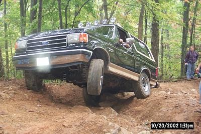 1990 Ford Bronco - This 1990 Ford Bronco is navigating a challenging off-road course in a wooded area.