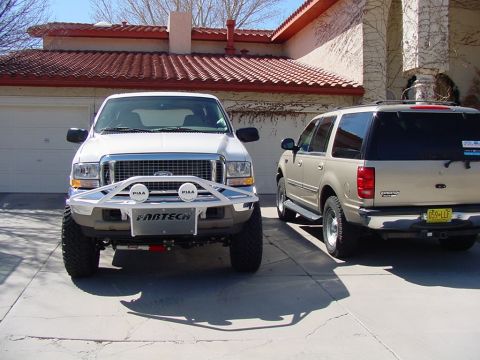 2002 Ford Excursion - A white 2002 Ford Excursion is parked next to a tan Ford Expedition in a driveway.