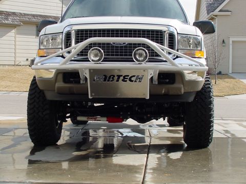 2002 Ford Excursion - Front view of a white 2002 Ford Excursion, modified with a brush guard and Fabtech branding on the bumper.