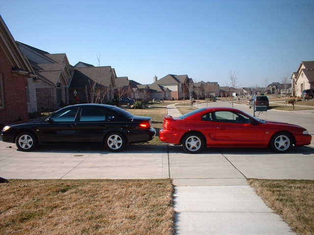 Black sedan and red coupe parked in a suburban driveway