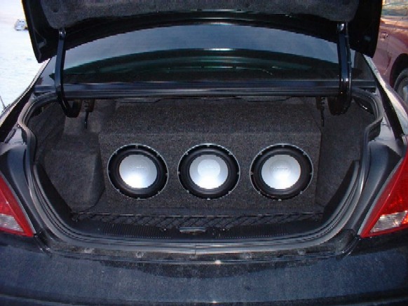Car trunk with three subwoofers in a ported box mounted in carpeted enclosure