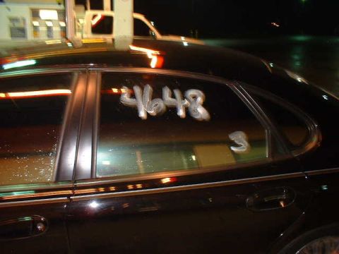 2000 Ford Taurus - Numbers 4648 and 3 are written on the side window of a black car.