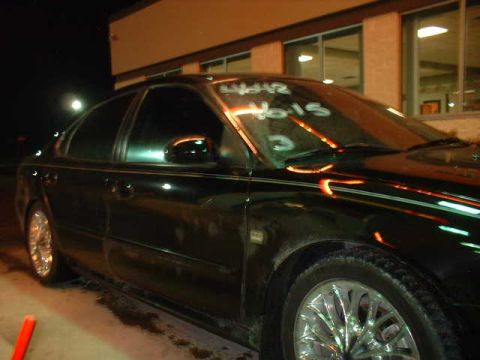 2000 Ford Taurus - A black sedan is parked outside a building at night, with writing on its windshield.