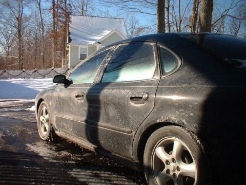 2000 Ford Taurus - A dirty, frost-covered 2000 Ford Taurus sedan is seen from the side on a winter day.