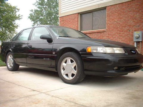 2000 Ford Taurus - This black sedan, likely a 1992 model, is parked in front of a brick building.