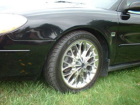 2000 Ford Taurus - Close-up of a black car's front fender and chrome wheel.