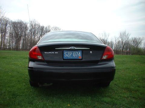 2000 Ford Taurus - Rear view of a black 2000 Ford Taurus SE sedan parked in a grassy field.