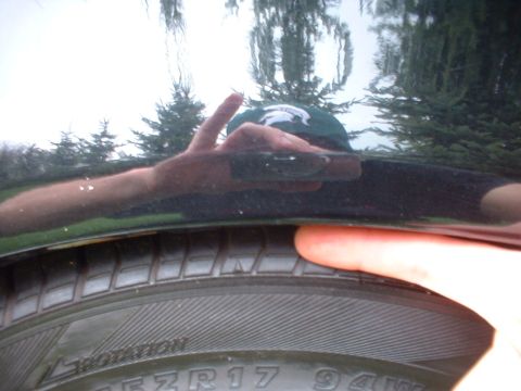2000 Ford Taurus - A hand presses on the tire of a black 2000 Ford Taurus, showing the wheel well gap.