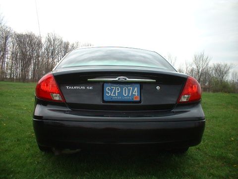 2000 Ford Taurus - Black 2000 Ford Taurus SE parked on grass with trees in the background.