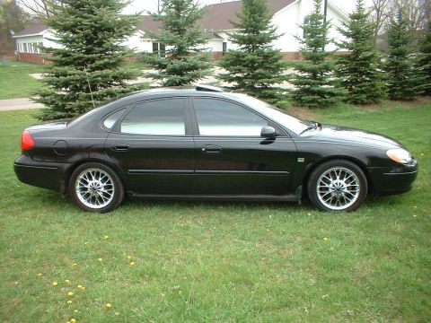 2000 Ford Taurus - Side view of a black 2000 Ford Taurus sedan on a sunny day.