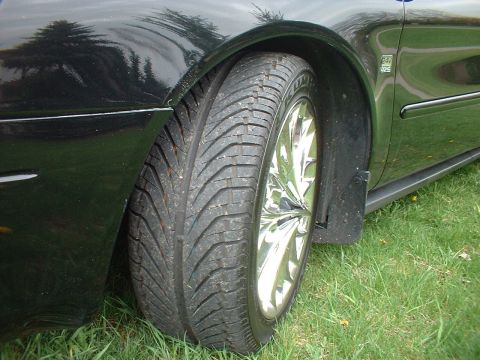 2000 Ford Taurus - A close-up view of a vehicle's side, focusing on the fender and tire with a chrome wheel.