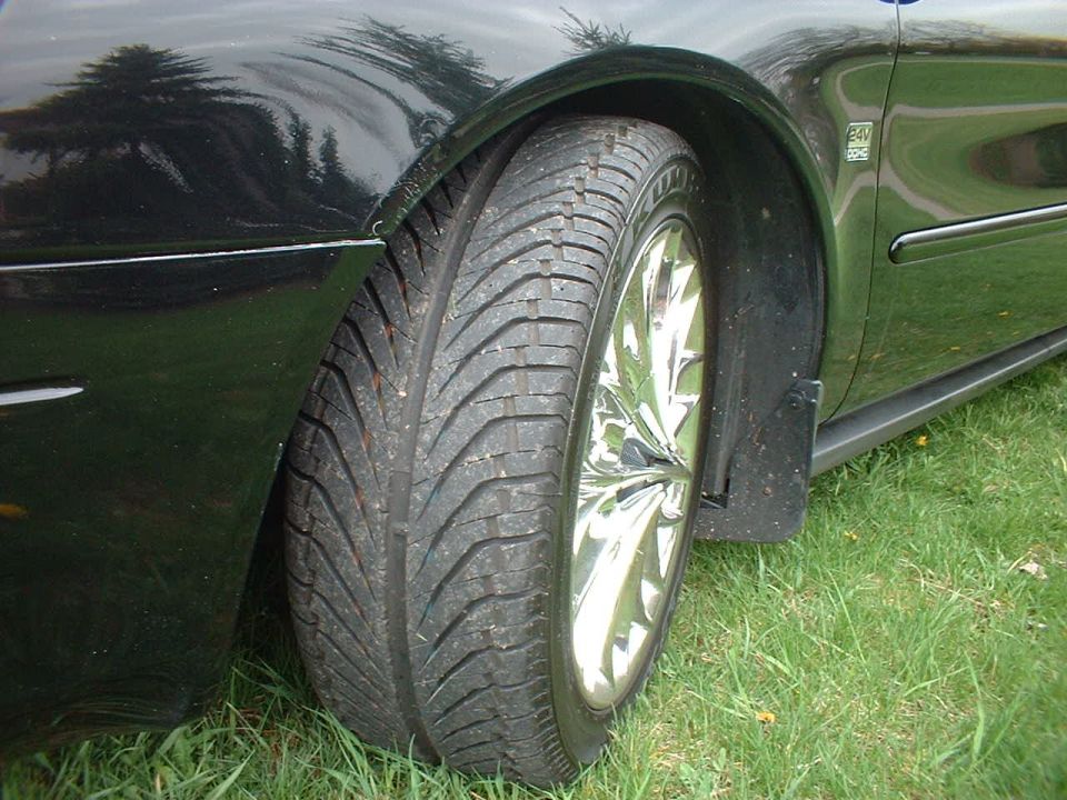 Close-up of a car's side, showing the fender, tire, and chrome wheel. There's a Supermotors.net watermark at the bottom right