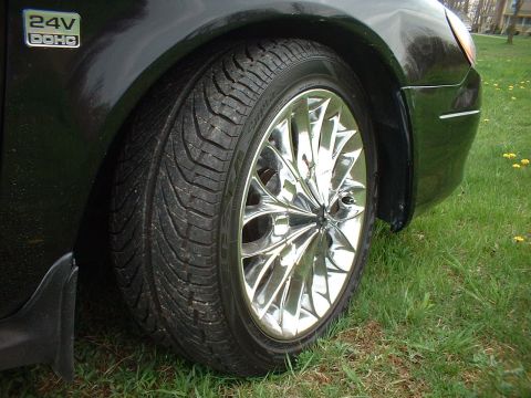 2000 Ford Taurus - A close-up view of a car's fender and a chrome wheel with a tire.