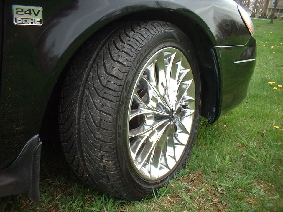 Black car fender and chrome wheel with a tire, close-up side view