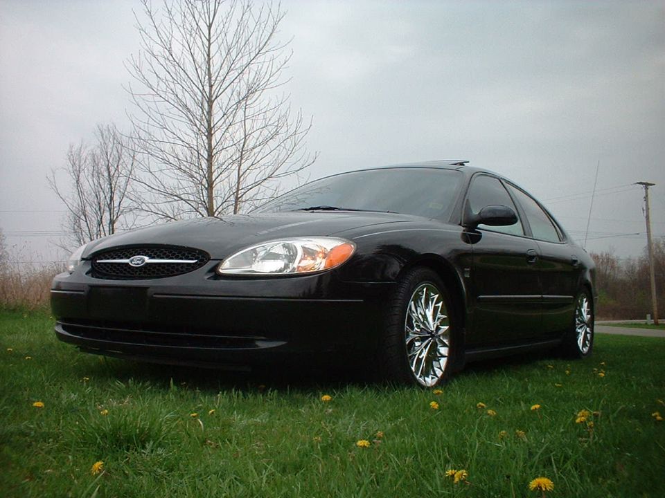 Black 2000 Ford Taurus sedan with chrome wheels parked on grass