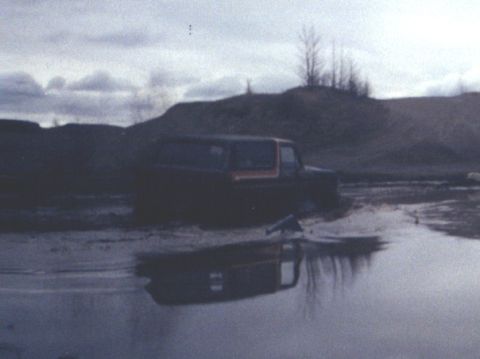 1978 Ford Bronco - 1978 Ford Bronco navigating a muddy terrain, its reflection visible in the water.