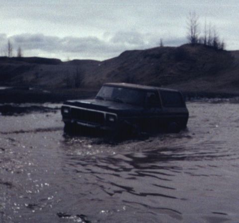 1978 Ford Bronco - A 1978 Ford Bronco navigates a water-filled terrain, kicking up spray.