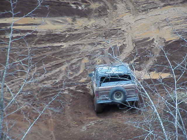 1978 Ford Bronco driving up a muddy hill, spare tire mounted on rear door