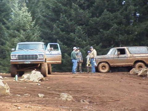 1978 Ford Bronco - Two 1978 Ford Broncos are seen off-road with a group of people gathered around them.