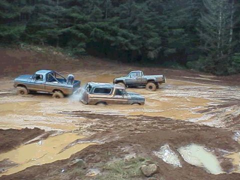 1978 Ford Bronco - Several trucks are bogged down in deep mud during an off-road adventure.
