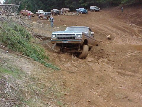 1978 Ford Bronco - A Ford F-Series truck navigates a muddy off-road course with other vehicles in the background.