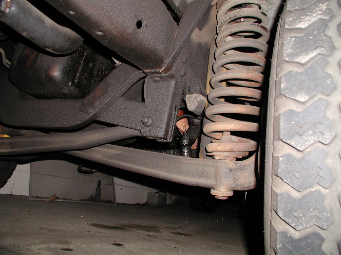 Underside view of front coil-spring suspension and control arm on a truck