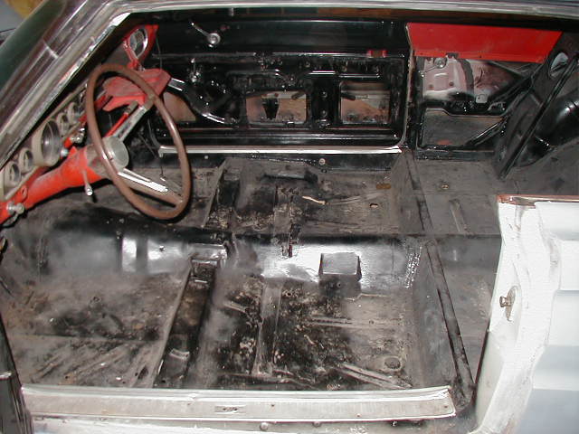 Stripped classic car interior with bare floor pans and red steering wheel