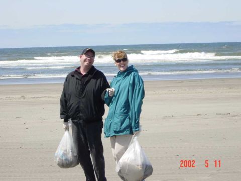 1996 Ford Bronco - Two people collect trash on the beach, with the ocean and waves in the background.