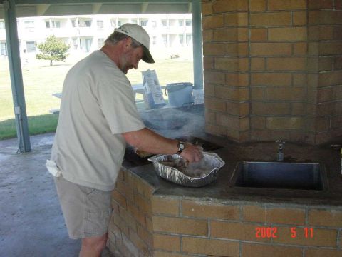 1996 Ford Bronco - A man prepares food at an outdoor brick grill, with a sink and a visible Supermotors.net watermark from 2002.