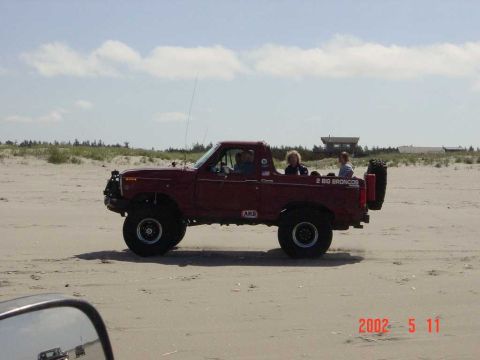 1996 Ford Bronco - This red Ford Bronco is seen on the beach with passengers in the open rear.