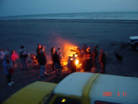 1996 Ford Bronco - Bonfire on the beach with people and vehicles.