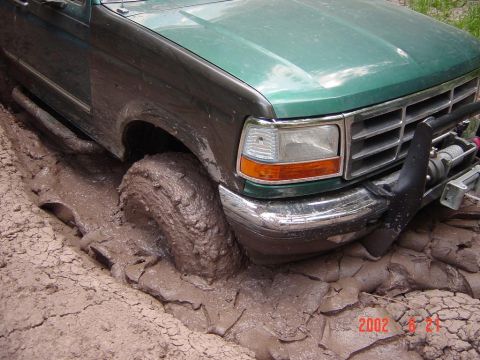 1996 Ford Bronco - This 1996 Ford Bronco is deep in the mud, showing off its off-road capabilities. A winch is mounted on the front bumper.