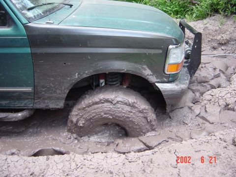 1996 Ford Bronco - This 1996 Ford Bronco is deep in the mud, with its front right tire almost completely covered.
