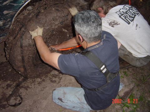 1996 Ford Bronco - Two men are working to extract a large, mud-encrusted object from the ground.