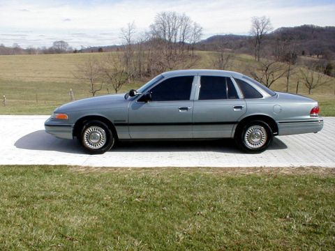 1995 Ford Crown Victoria - A silver 1995 Ford Crown Victoria is shown from the side, parked outdoors on a paved surface.
