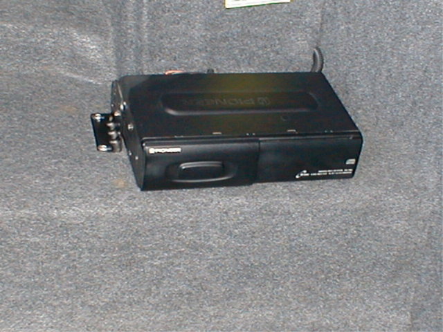 Black Pioneer CD changer unit sitting on gray carpet in a trunk