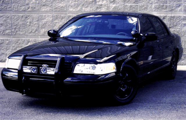 Black Ford Crown Victoria sedan, 3/4 front view, with push bar and black steel wheels